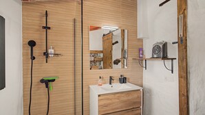 Une salle de bain moderne avec un meuble-lavabo en bois, un grand miroir et un espace douche.
