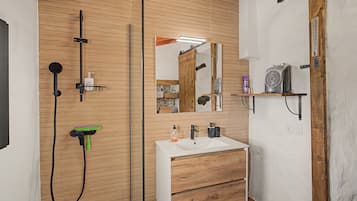 Een moderne badkamer met een houten wastafelmeubel, een grote spiegel en een douchehoek.