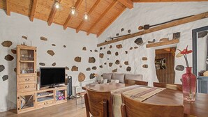 Un intérieur rustique avec des murs en pierre apparentes, des meubles en bois et un coin repas.