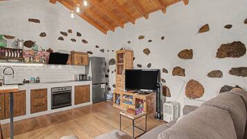 Una cocina rústica con armarios de madera, horno empotrado y pared de piedra.