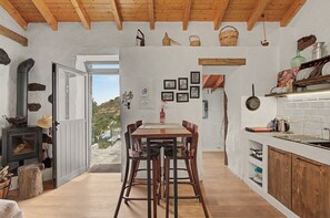 Eine rustikale Küche mit einem Holztisch, Stühlen und Blick ins Freie.