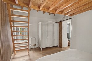 Ein Schlafzimmer mit Holzboden, einem Kleiderschrank, einem Bett und einem Fenster mit Blick.