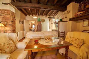 Uma sala de estar acolhedora com uma mesa de madeira, dois sofás, uma parede de tijolos e um teto rústico.