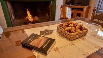 Una mesa con un libro, una cesta de flores y una chimenea al fondo.