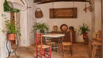 Une pièce rustique avec une table en bois, deux chaises rouges et des plantes en pot.