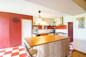 A kitchen with a wooden island, a hanging light fixture, and a red and white checkered floor.