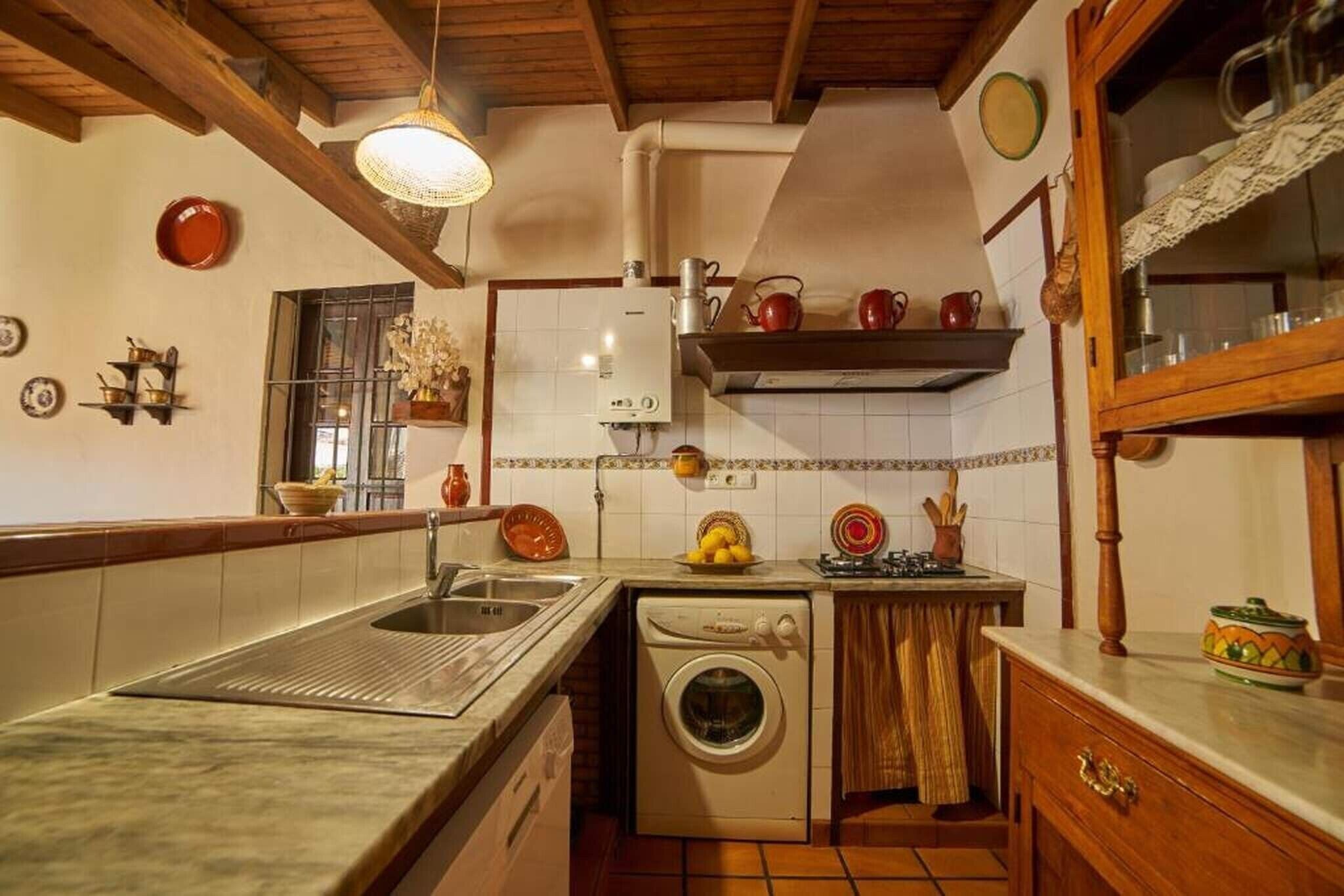 A kitchen with a washing machine, sink, and various kitchenware.
