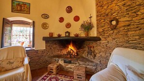 A cozy room with a stone fireplace, a sofa, a window with a view, and various wall decorations.
