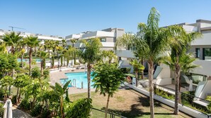Ein modernes Hotel mit Swimmingpool, umgeben von Palmen und viel Grün.