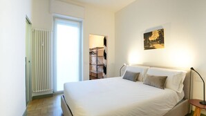 Ein Schlafzimmer mit Bett, Nachttisch, Wandbild und Heizkörper.