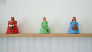 Drei Figuren auf einem Regal vor einer weißen Wand.