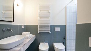Ein modernes Badezimmer mit einem großen weißen Waschbecken, einem Bidet und einer Toilette.
