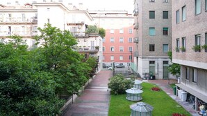 A courtyard with a paved walkway, green lawn, and outdoor seating areas.