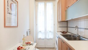 A compact kitchen with a dining area, featuring a double door, a washing machine, and a sink.
