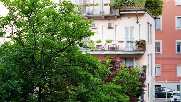 A multi-story building with balconies, some with plants.