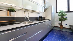 A modern kitchen with a stainless steel sink, a built-in oven, and a window with blinds. - Milano, Industrial Loft (Milano)