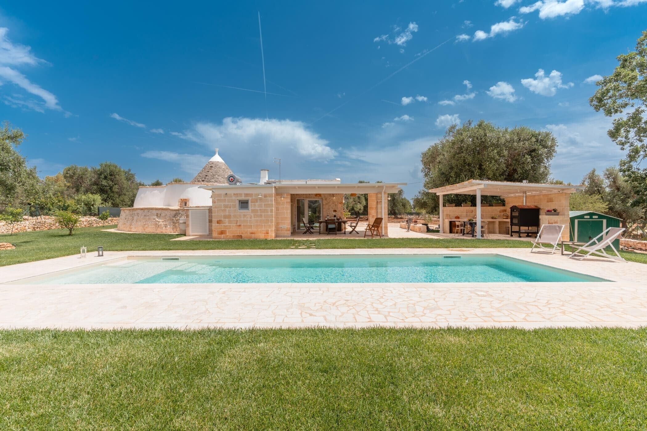 Ein Haus mit Schwimmbad, Außenbereich und überdachter Terrasse.