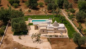 Vue aérienne d’une propriété comprenant une piscine, un kiosque et un bâtiment en pierre.