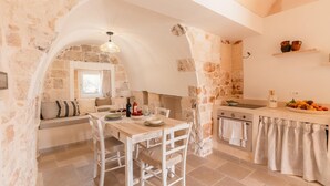 Une cuisine rustique avec des murs en pierre, une table à manger en bois et un four encastré.