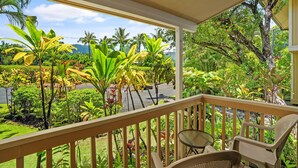 Un balcon donnant sur une végétation luxuriante et une route.