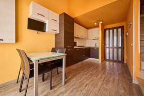 A modern kitchen with wooden cabinets, a dining table with chairs, and a microwave.