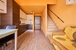 A modern kitchen with wooden cabinets, a dining table, and a staircase leading to an upper floor.