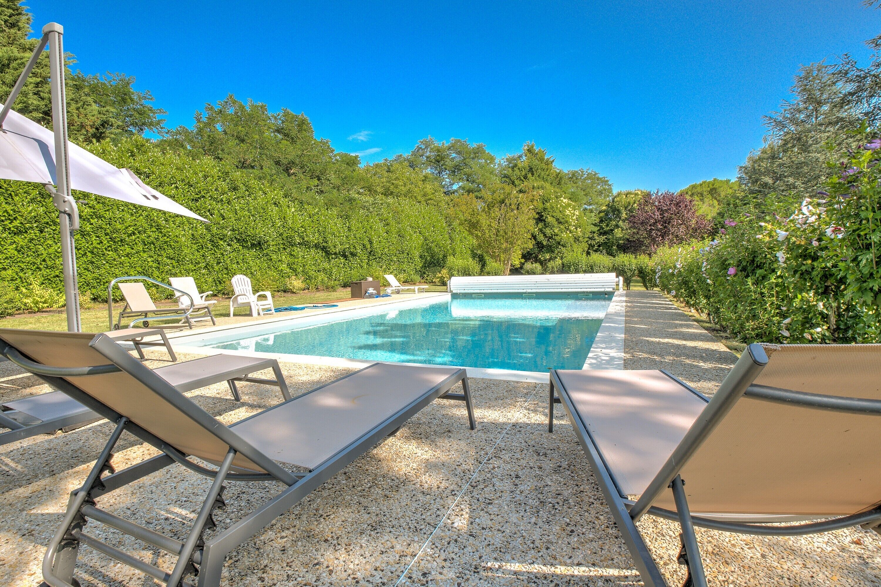 A swimming pool with lounge chairs and a pergola.