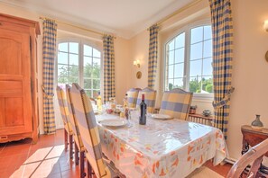 Une salle à manger avec une table dressée pour quatre personnes, un buffet en bois et une fenêtre avec des rideaux.