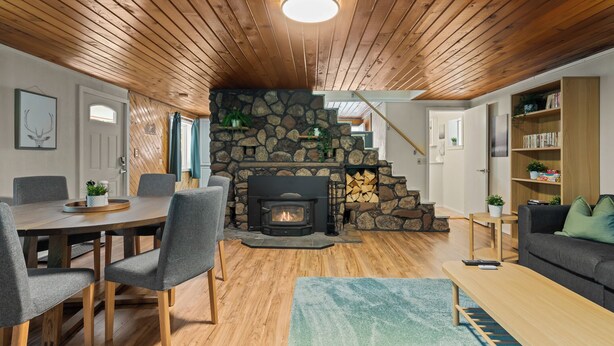 Ein gemütliches Wohnzimmer mit Kamin, Holzboden und einem Essbereich mit Stühlen und Tisch.