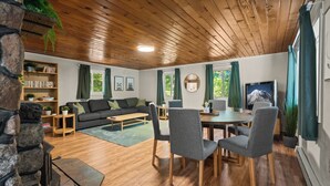 Ein gemütliches Wohnzimmer mit Kamin, einer Couch, einem Esstisch mit Stühlen und einem Bücherregal.