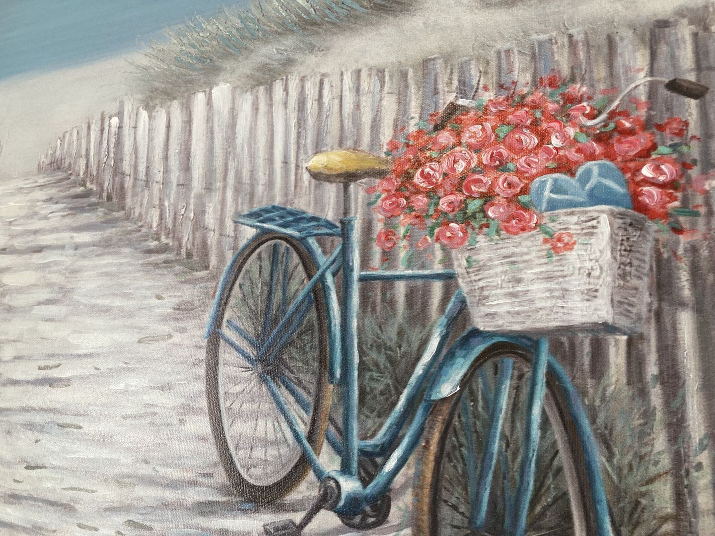 Una bicicleta con una cesta de flores estacionada junto a una valla de madera.