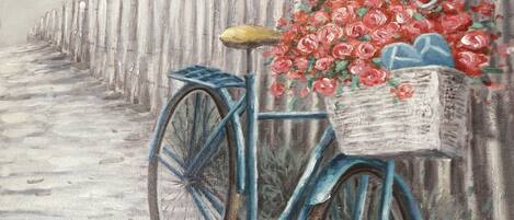 Una bicicleta con una cesta de flores estacionada junto a una valla de madera.