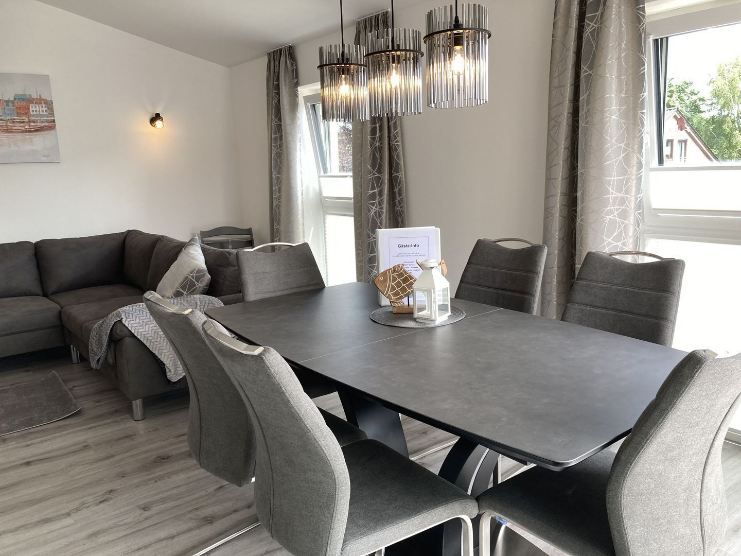Un comedor moderno con una mesa oscura, sillas tapizadas en gris y un farol decorativo con forma de pez.