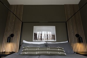Une chambre moderne avec un grand lit, une œuvre d’art accrochée au mur et deux lampes de chevet.