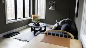 Una habitación con una mesa de madera, una silla, un sofá y una mesita redonda con una planta.