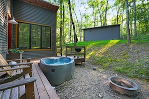 Une terrasse en bois avec un jacuzzi, un petit abri de jardin et une chaise en bois.
