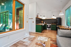 Eine moderne Küche mit Kochinsel, Holzboden und einem Essbereich mit grauem Sofa und Tisch.