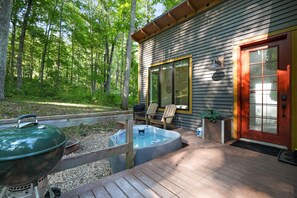 Une terrasse en bois avec un jacuzzi, un barbecue et un espace salon extérieur.