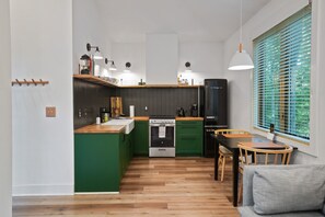 Une cuisine moderne avec des meubles de couleur verte, un plan de travail en bois et un four encastré.