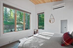 Un dormitorio con ventanas amplias, una cama, un espejo colgado y un equipo de aire acondicionado.