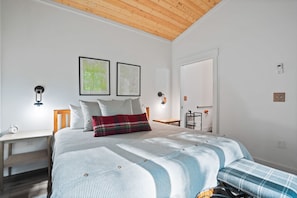 Une chambre à coucher avec un lit, une table de chevet, une chaise, une petite table et une porte.