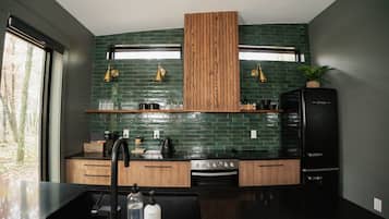 A modern kitchen with a black countertop, wooden cabinets, and a green-tiled backsplash.