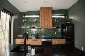 Et moderne køkken med en sort bordplade, træskabe og en backsplash i grønne fliser.
