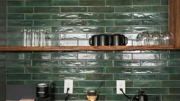 Een keuken met een groene betegelde achterwand, houten kastjes en een zwart aanrecht.