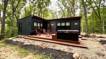 Een chalet met terras, buitenmeubilair en een hottub.