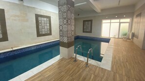 Una piscina interior amb parets de rajola i sòl de fusta.