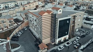 Un edifici d'apartaments modern amb un pati central, nombroses balconades i una zona d'aparcament.