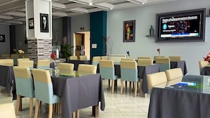 Una sala de conferències amb taules i cadires, una pantalla que mostra una presentació i quadres a les parets.