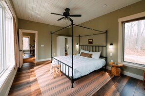 A four-poster bed with a ceiling fan, a large window, and a wooden floor. - Ivy Cottage | Hocking Hills, Modern, Hot Tub (Creola)