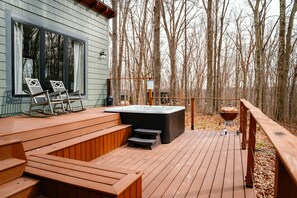 A wooden deck with a hot tub, barbecue grill, and rocking chairs. - Ivy Cottage | Hocking Hills, Modern, Hot Tub (Creola)